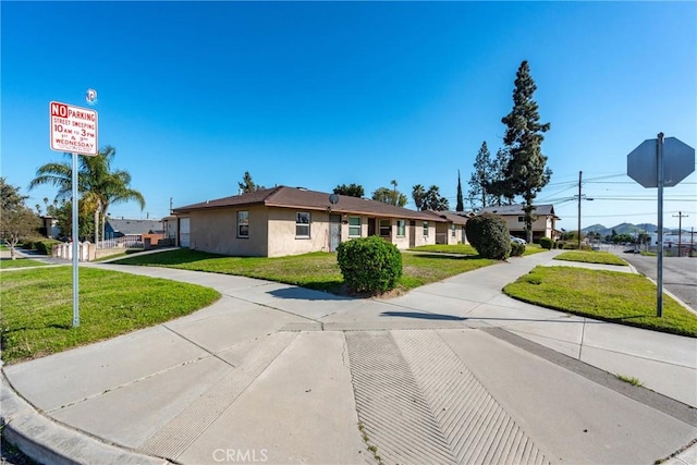 single story home featuring stucco siding and a front lawn