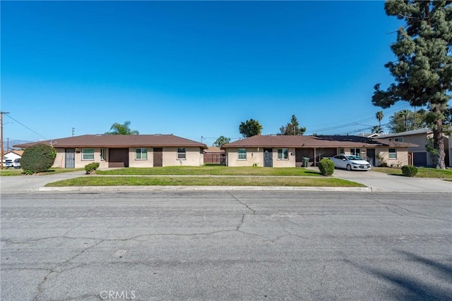 single story home featuring stucco siding, concrete driveway, and a front lawn