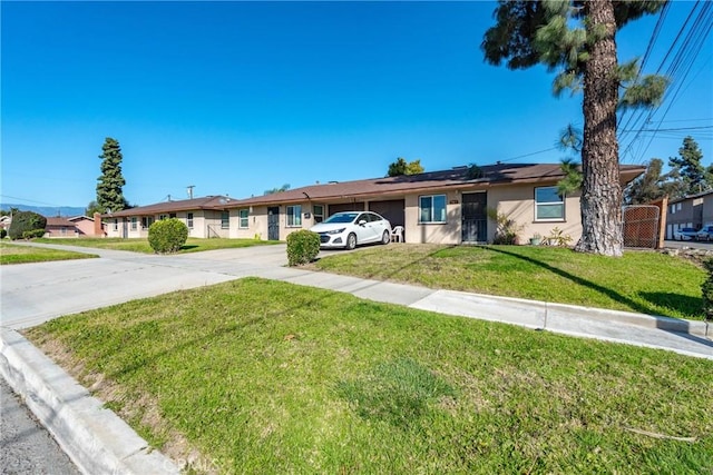 ranch-style home with stucco siding, driveway, fence, a front yard, and solar panels