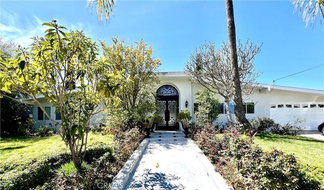 view of front of property with stucco siding, an attached garage, and a front yard
