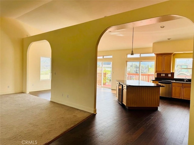 kitchen featuring a kitchen island, open floor plan, arched walkways, dishwasher, and dark wood-style flooring