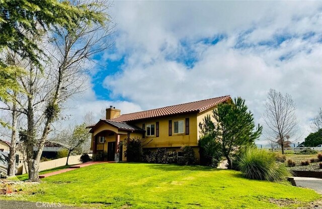 view of front of home with a front yard, stucco siding, fence, and a chimney
