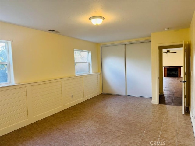 unfurnished bedroom with visible vents, multiple windows, a closet, and wainscoting
