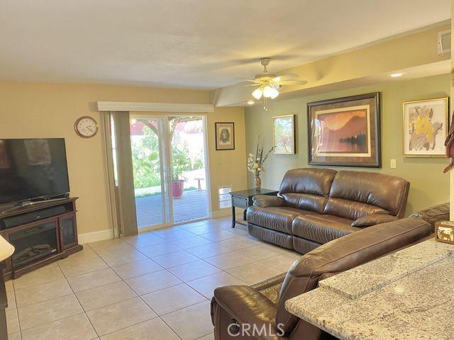 living room with light tile patterned floors, a ceiling fan, and baseboards