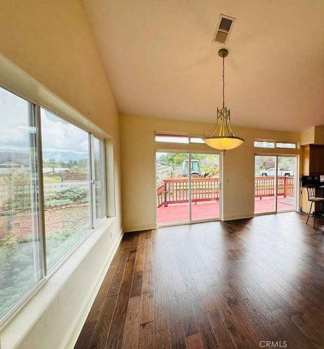 spare room featuring lofted ceiling, plenty of natural light, visible vents, and dark wood-style flooring