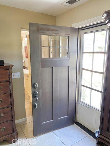 doorway to outside with light tile patterned floors, visible vents, and baseboards