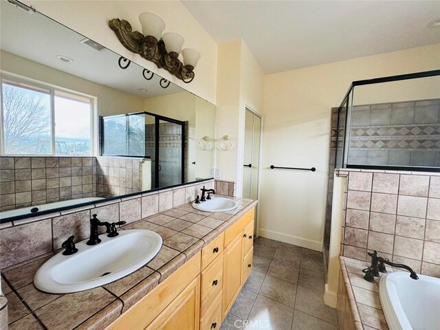 full bathroom featuring tile patterned floors, a shower stall, a garden tub, and a sink