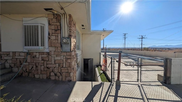 exterior space with fence, a gate, stucco siding, and stone siding