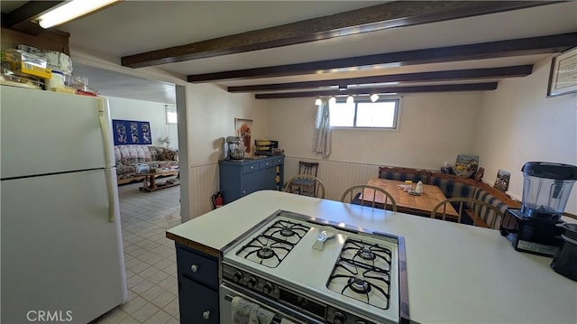 kitchen with white appliances, beamed ceiling, light floors, and wainscoting