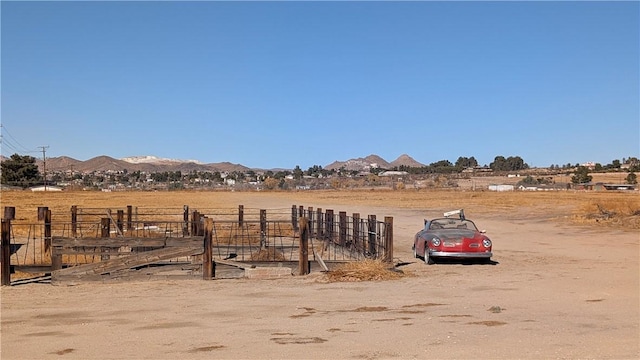 view of yard featuring a rural view, a mountain view, and fence
