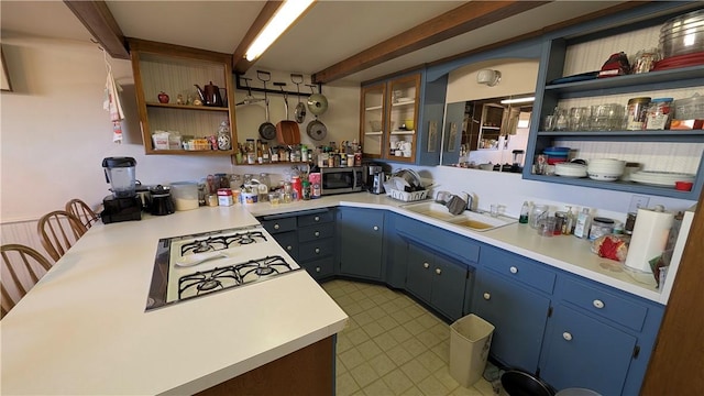 kitchen with stainless steel microwave, beam ceiling, a sink, open shelves, and blue cabinets