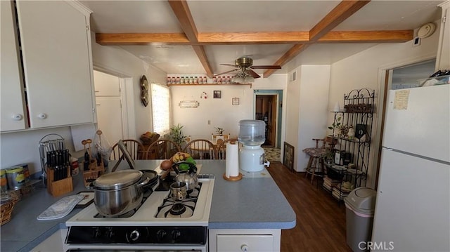 kitchen with a ceiling fan, visible vents, white appliances, beamed ceiling, and dark wood-type flooring