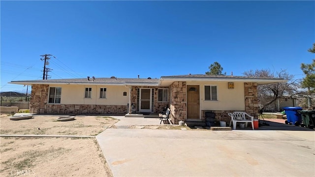 ranch-style house featuring stucco siding and stone siding