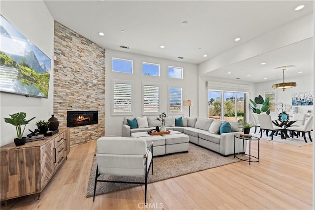 living area with light wood-type flooring, visible vents, a fireplace, and recessed lighting