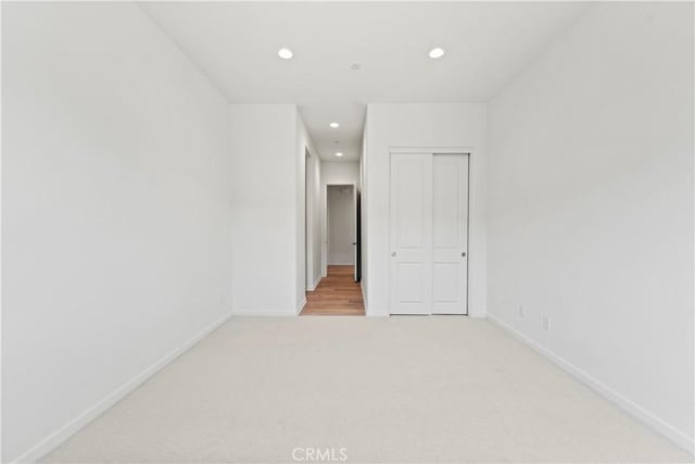 unfurnished bedroom with baseboards, a closet, recessed lighting, and carpet floors