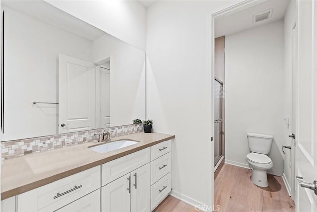 full bath with toilet, wood finished floors, vanity, visible vents, and decorative backsplash