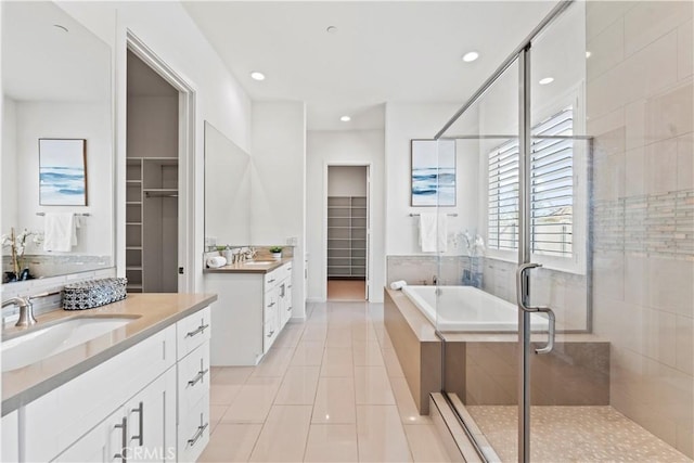 bathroom featuring tile patterned flooring, a stall shower, two vanities, and a sink