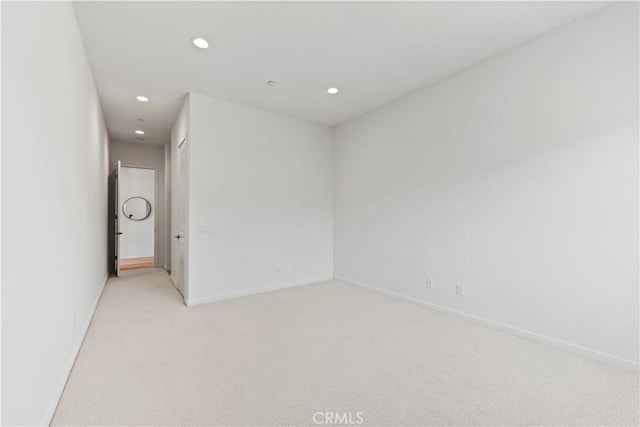 spare room with light colored carpet, baseboards, and recessed lighting