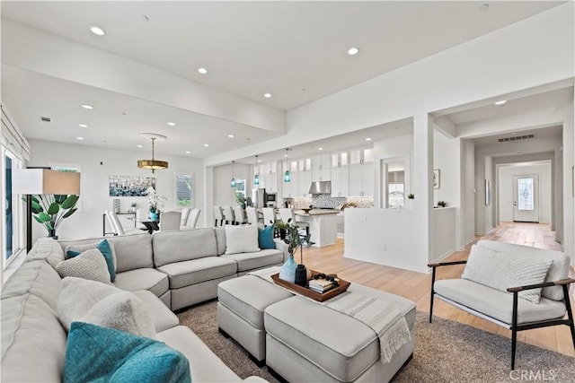 living area featuring light wood finished floors, recessed lighting, and visible vents
