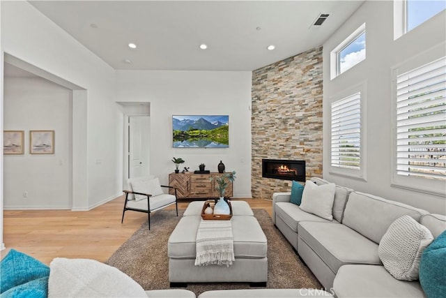 living area with recessed lighting, baseboards, visible vents, a fireplace, and light wood-type flooring