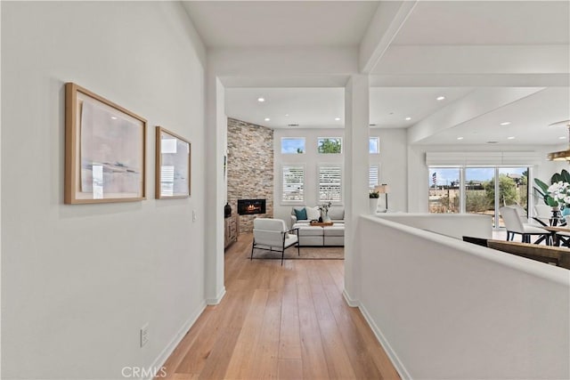 hallway featuring light wood finished floors, baseboards, and plenty of natural light