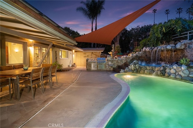 pool at dusk featuring area for grilling, an outdoor pool, outdoor dining space, and a patio