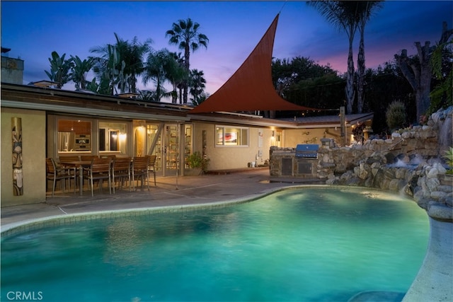 pool with area for grilling, an outdoor kitchen, and a patio