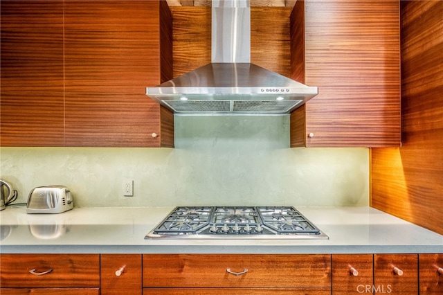 kitchen with stainless steel gas cooktop, light countertops, and wall chimney range hood