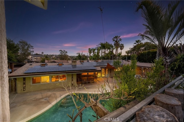 back of house featuring solar panels, an outdoor pool, a patio, and stucco siding