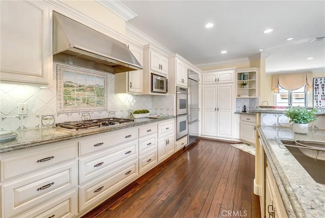 129 Via Waziers, Newport Beach, CA 92663 - kitchen with stainless steel appliances, exhaust hood, dark wood-type flooring, light stone counters, and backsplash