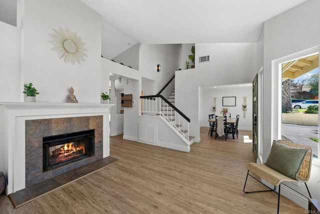 entryway featuring high vaulted ceiling, stairs, light wood-style flooring, and visible vents