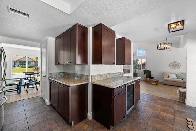 kitchen with visible vents, stone tile floors, wine cooler, baseboards, and a textured ceiling