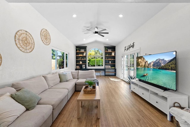 living room with built in features, vaulted ceiling, a wealth of natural light, and wood finished floors