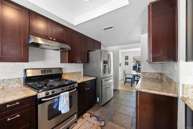 kitchen featuring under cabinet range hood, stainless steel appliances, visible vents, and decorative backsplash