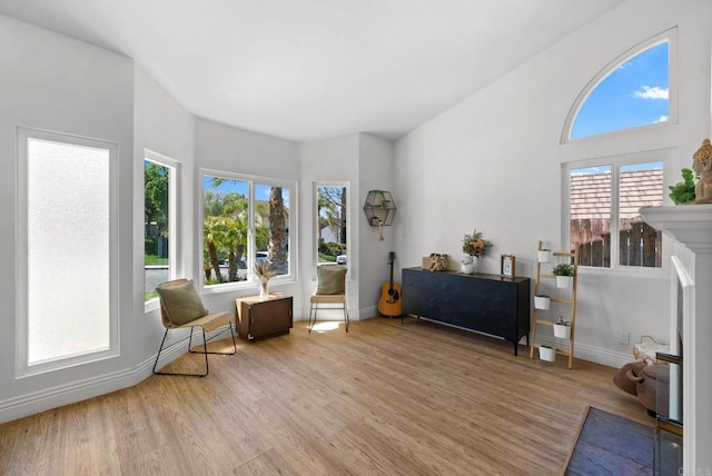 living area with a fireplace with flush hearth, baseboards, and light wood-type flooring