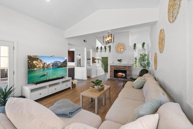 living area with a chandelier, vaulted ceiling, wood finished floors, and a fireplace