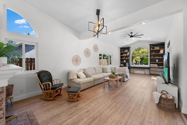 living room with built in shelves, ceiling fan with notable chandelier, baseboards, lofted ceiling, and light wood-type flooring