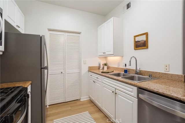 kitchen with stainless steel dishwasher, white cabinets, light wood-type flooring, a sink, and visible vents