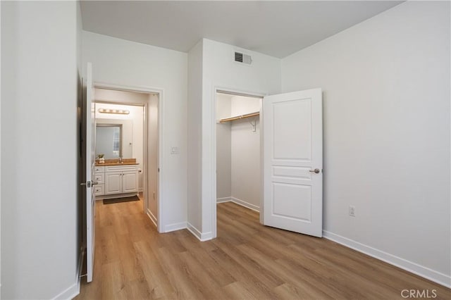unfurnished bedroom featuring light wood finished floors, a closet, visible vents, and baseboards