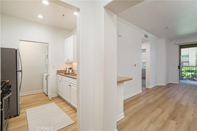 kitchen featuring white cabinets, ornamental molding, light wood finished floors, visible vents, and stainless steel gas range