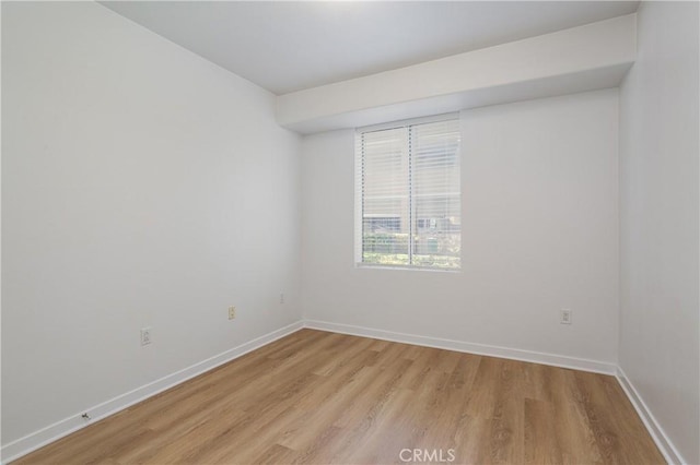 spare room with baseboards and light wood-type flooring