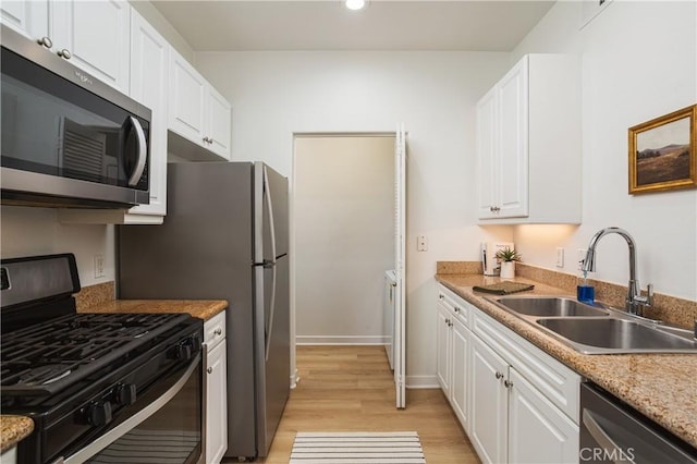 kitchen with white cabinetry, stainless steel appliances, light wood-type flooring, and a sink