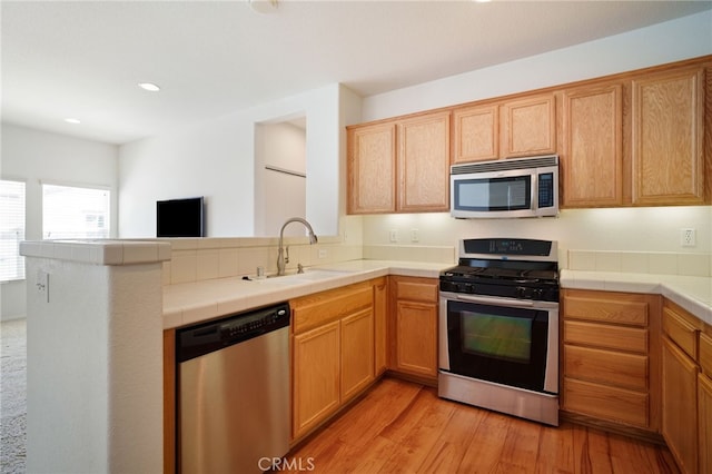 36337 Vincenzo Way, Winchester, CA 92596 - kitchen featuring appliances with stainless steel finishes, a peninsula, light wood-type flooring, tile counters, and recessed lighting