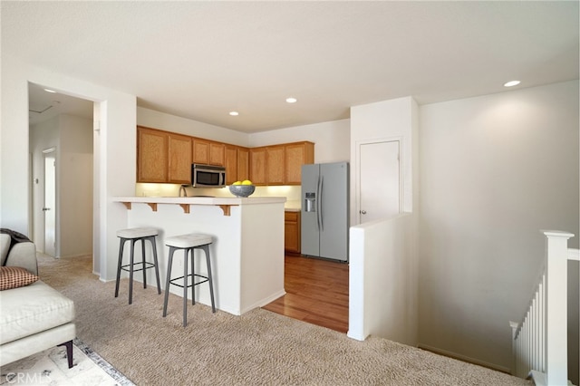 36337 Vincenzo Way, Winchester, CA 92596 - kitchen featuring appliances with stainless steel finishes, light carpet, a kitchen breakfast bar, a peninsula, and light countertops