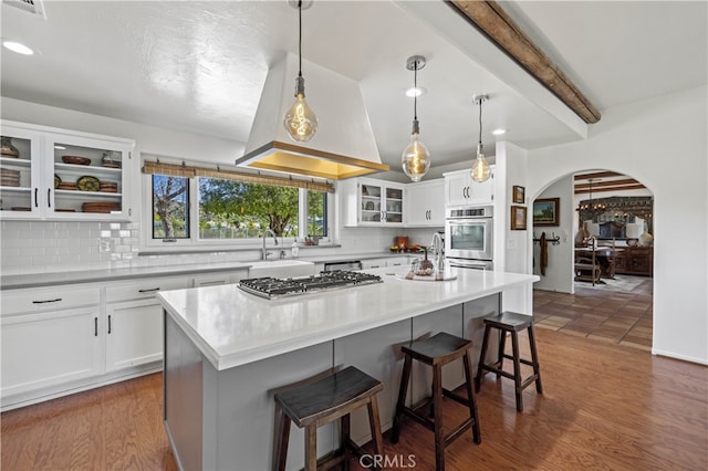 kitchen with backsplash, white cabinets, appliances with stainless steel finishes, and a kitchen breakfast bar