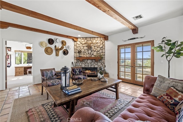 living area with light tile patterned floors, a stone fireplace, visible vents, french doors, and beam ceiling
