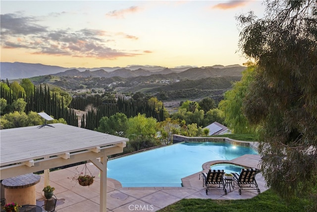 view of pool with a mountain view, an infinity pool, an in ground hot tub, and a patio area