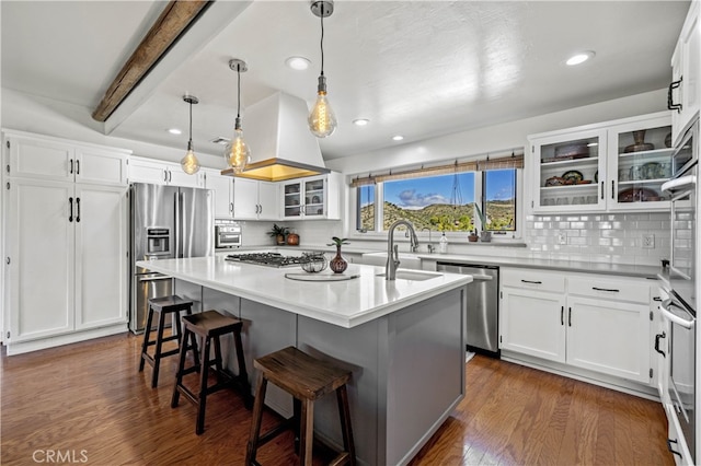 kitchen with tasteful backsplash, appliances with stainless steel finishes, a kitchen bar, white cabinetry, and a center island with sink