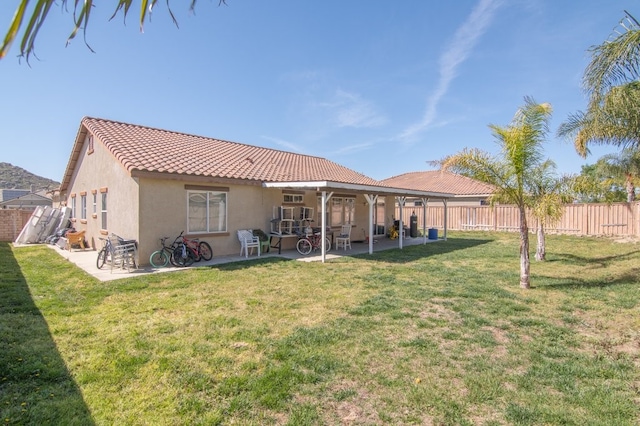 974 Saw Tooth Ln, Hemet, CA 92545 - rear view of house featuring a tiled roof, stucco siding, a lawn, a fenced backyard, and a patio