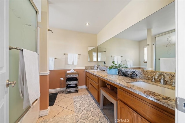 bathroom featuring tile patterned floors, double vanity, baseboards, and a sink